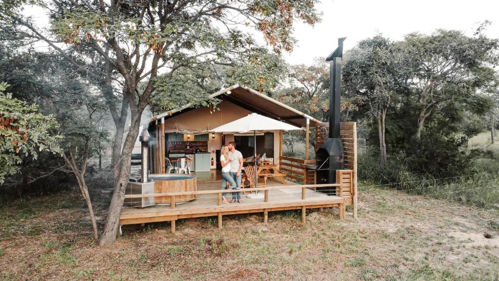 un homme debout sur une terrasse couverte d'une maison dans l'établissement AfriCamps Waterberg, à Vaalwater