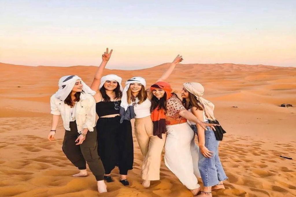 a group of women standing in the desert at Sahara Desert Camp in Merzouga