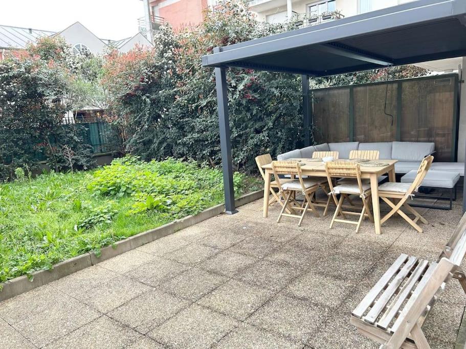 une table et des chaises en bois sous un auvent bleu dans l'établissement Appartement confort avec Jardin, à Saint-Denis