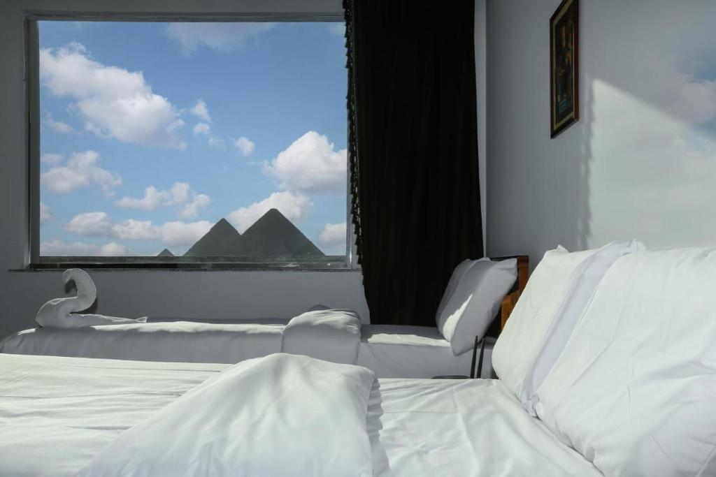 a bedroom with a bed and a large window at NEW ASSER HOTEL PYRAMID in Cairo