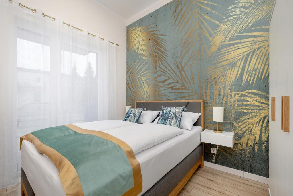 una camera da letto con un grande letto e carta da parati tropicale di Unique Apartment with Balcony in Swinoujscie by Rent like home a Świnoujście