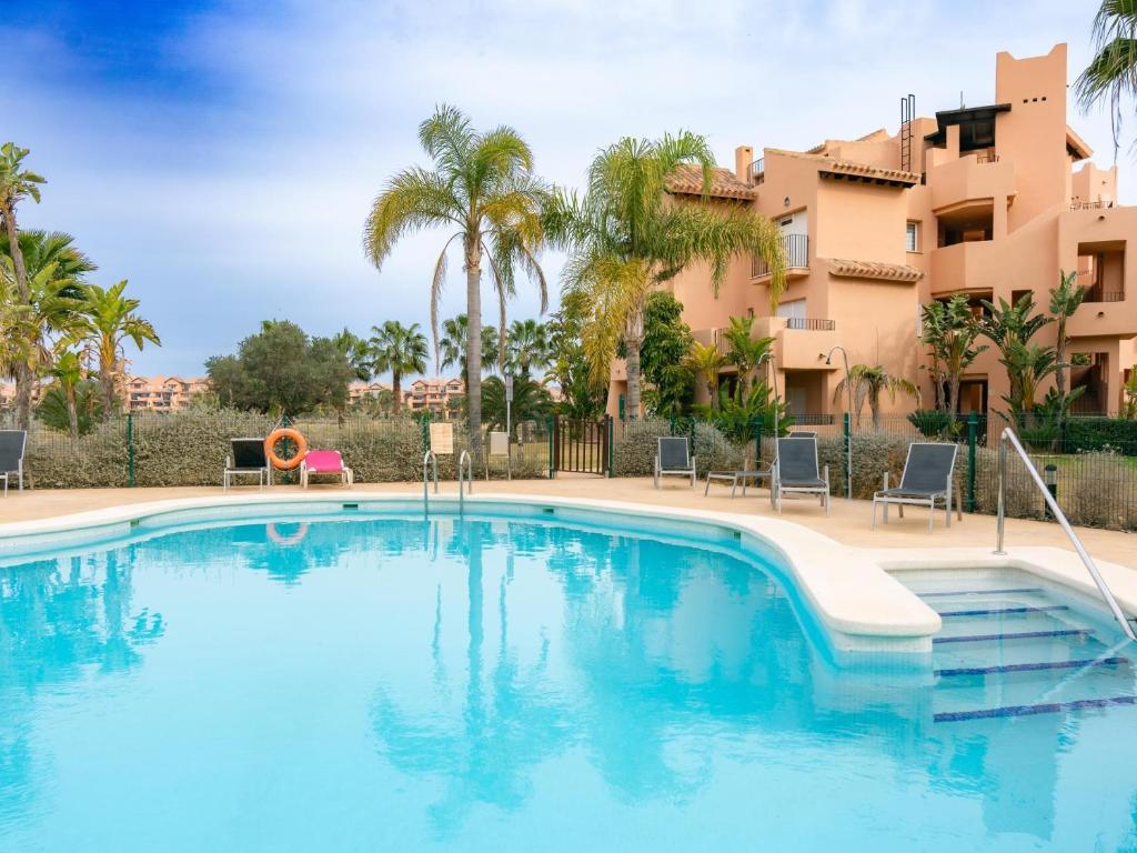 een zwembad met palmbomen en een gebouw bij Sun and Golf Apartment by Rentalole in Torre-Pacheco
