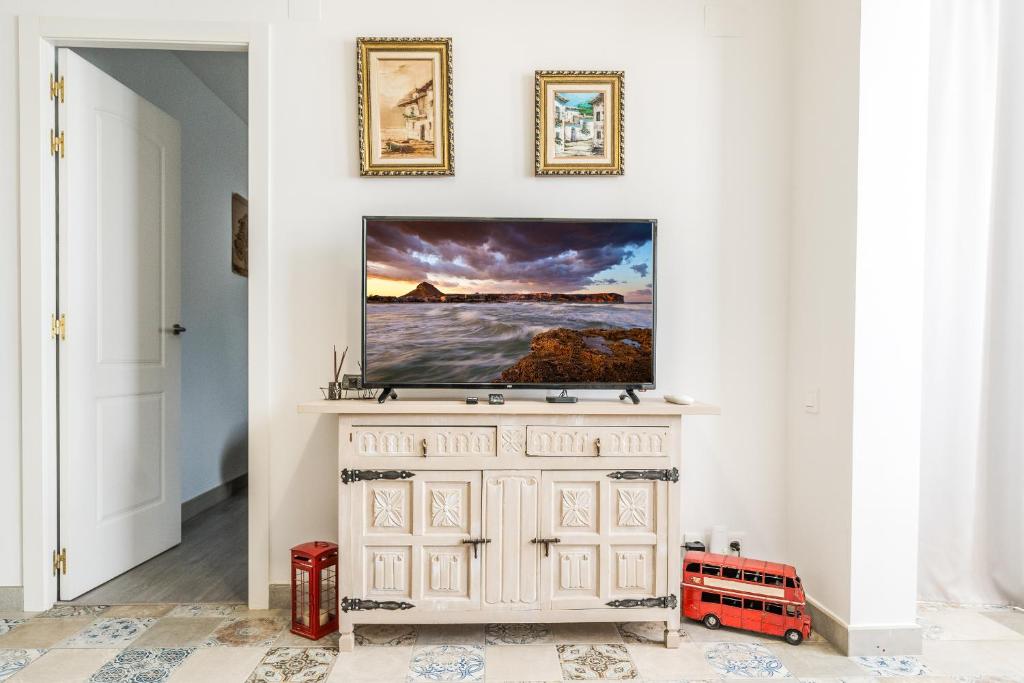 uma sala de estar com televisão numa parede branca em Happy house Arenal em Xàbia