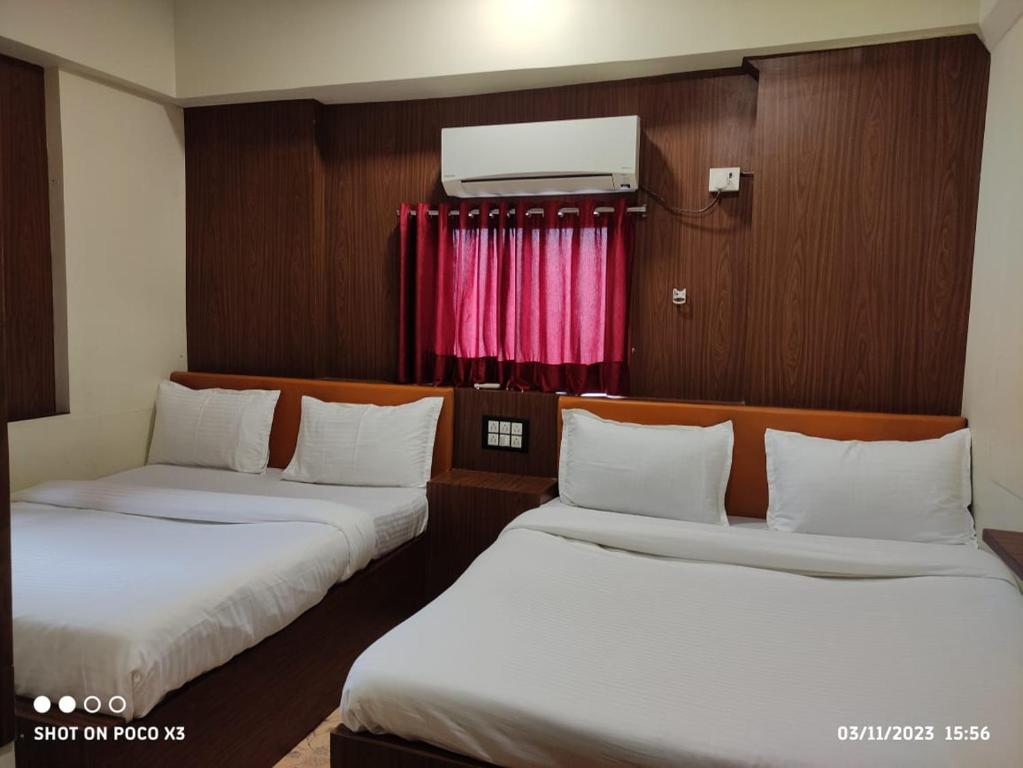 two beds in a small room with a window at Amber Guest House in Mumbai