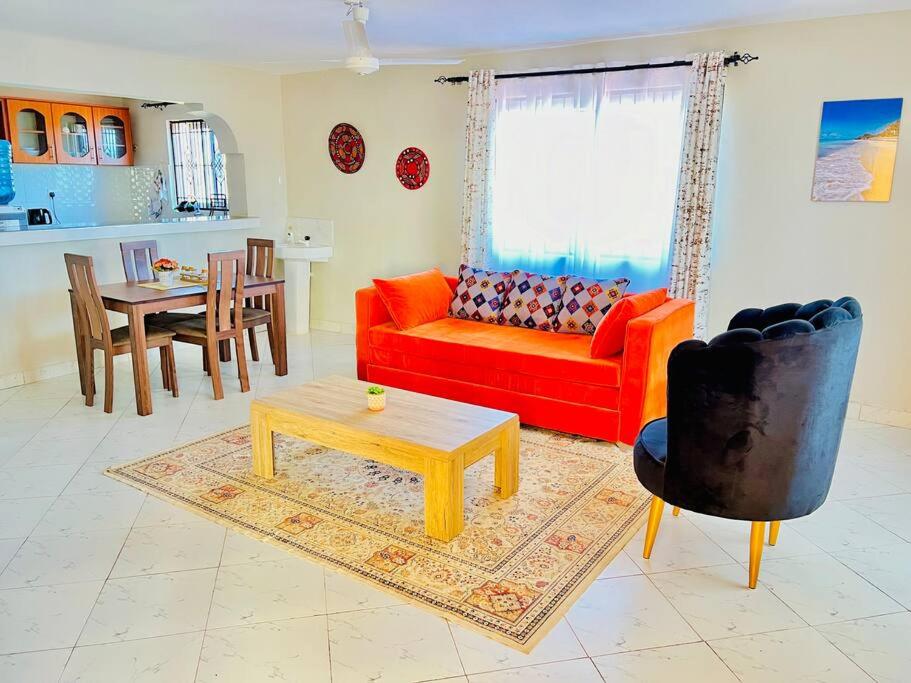 ein Wohnzimmer mit einem roten Sofa und einem Tisch in der Unterkunft Autumn House DIani in Ukunda