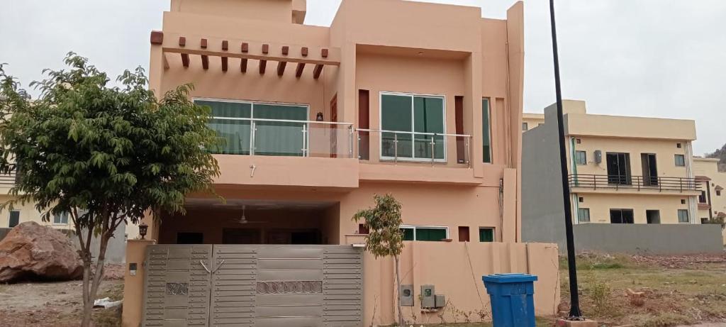 a pink house with a fence in front of it at Haven Lodge, cheerful 3BHK in Bahria Enclave in Islamabad
