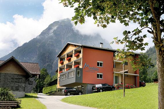 a large building with a mountain in the background at Hotel Garni Madrisa in Brand