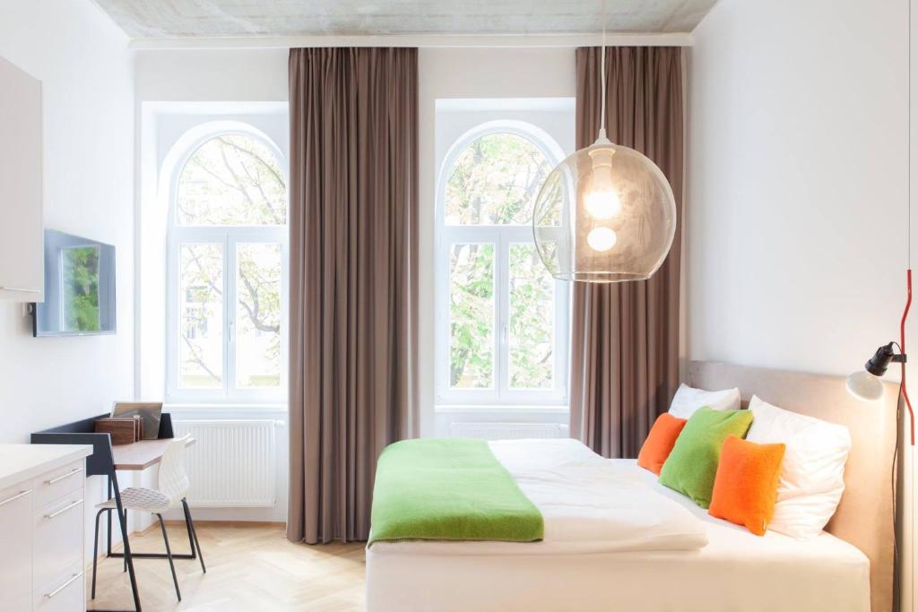 um quarto com uma cama branca e almofadas coloridas em KS70 Apartments em Viena