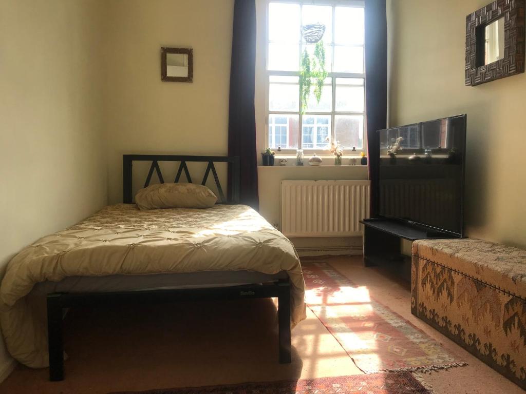 um quarto com uma cama e uma janela em Guinness Court Shared Apartment em Londres