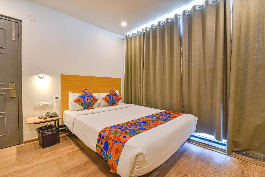 um quarto com uma cama grande e uma janela em FabHotel NY Townhouse em Ahmedabad