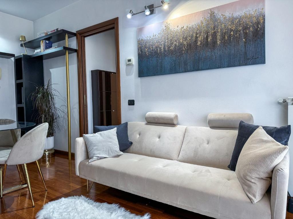 a living room with a white couch and a painting on the wall at Luxury White Apartment BGY - Orio al Serio Airport in Zanica