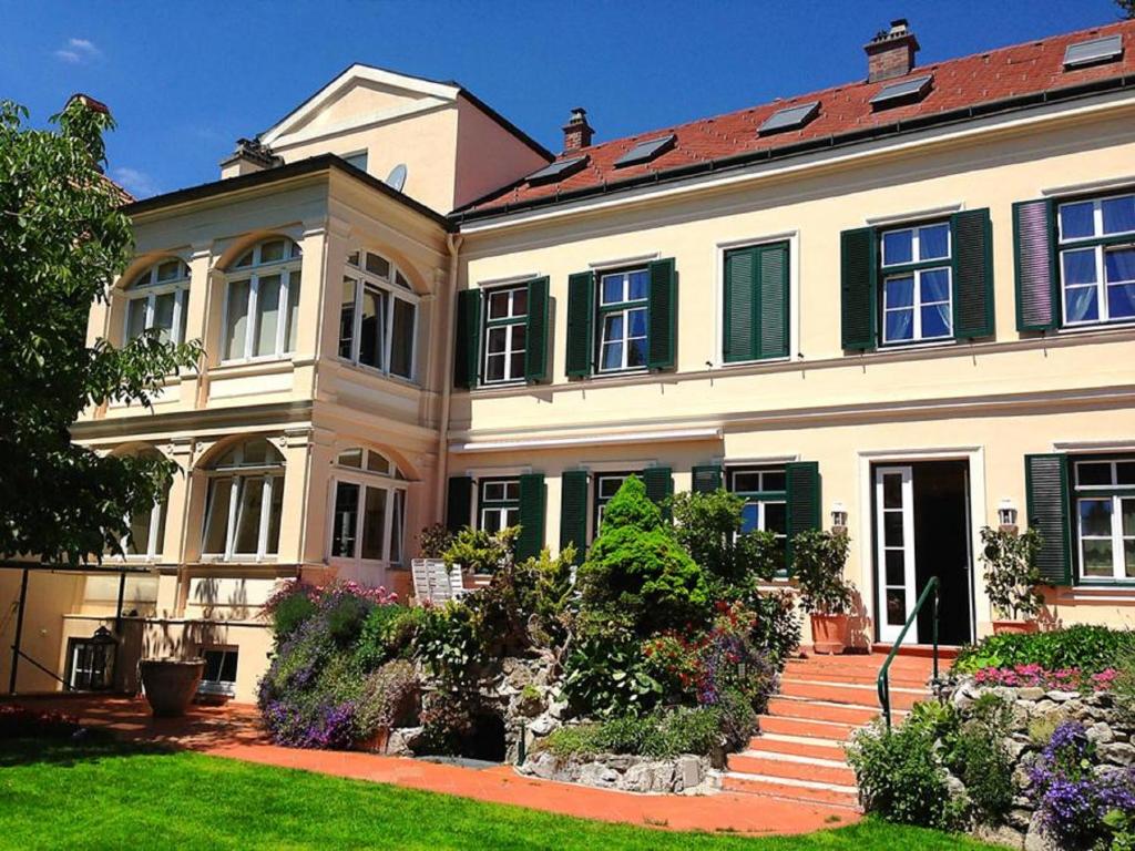 Casa blanca grande con ventanas verdes y patio en Förster Appartements, en Bad Vöslau