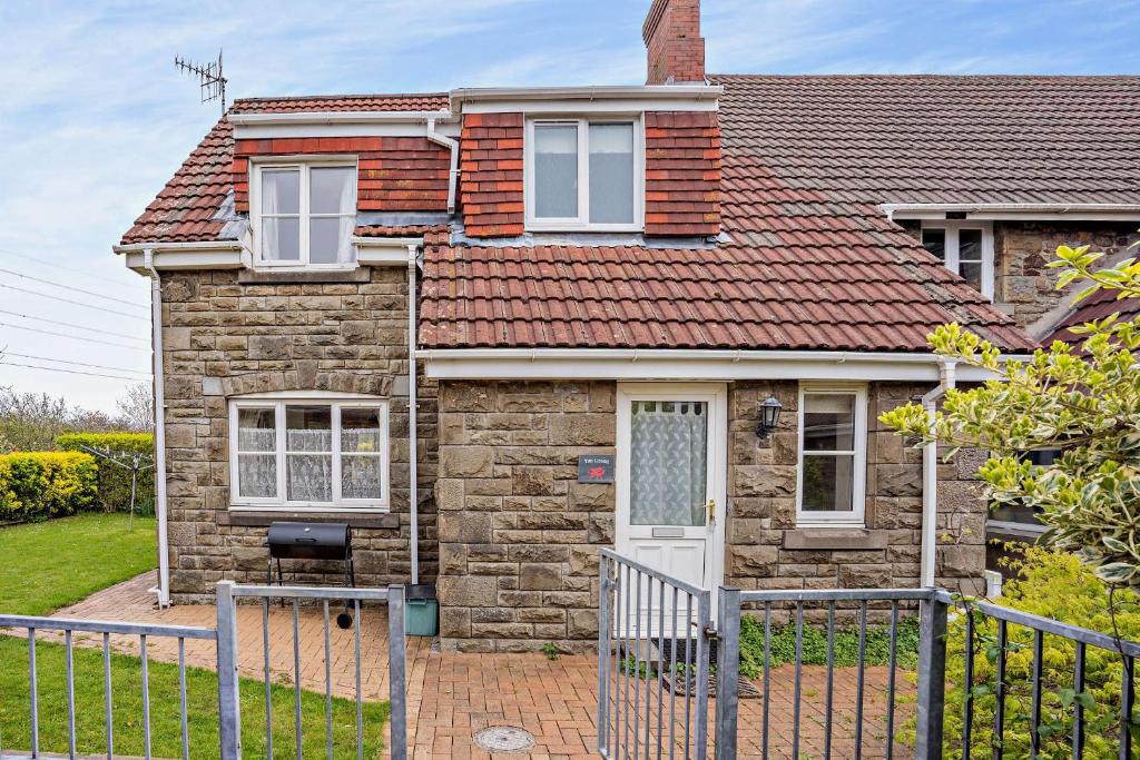 a brick house with a fence in front of it at Tyncellar Farm holiday cottages in Margam