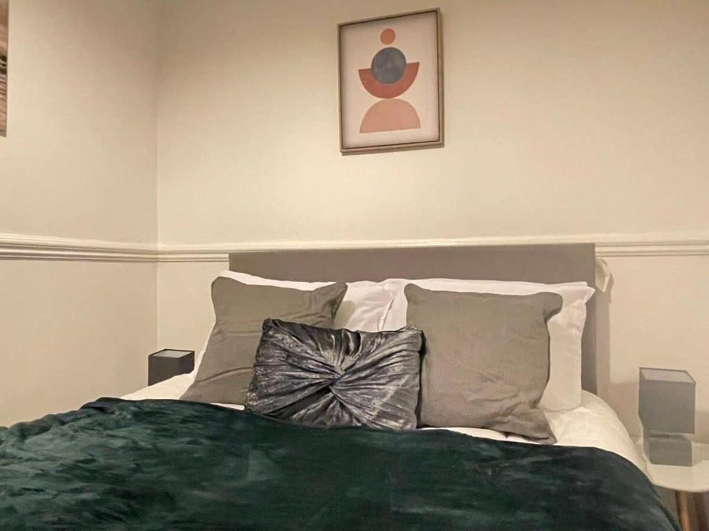 a bedroom with a bed with a green blanket and pillows at Cosy home with FREE PARKING and fast internet in Portsmouth