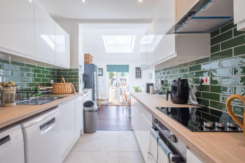 een keuken met witte kasten en groene tegels bij Central 4 Bed Home With Parking in Cambridge