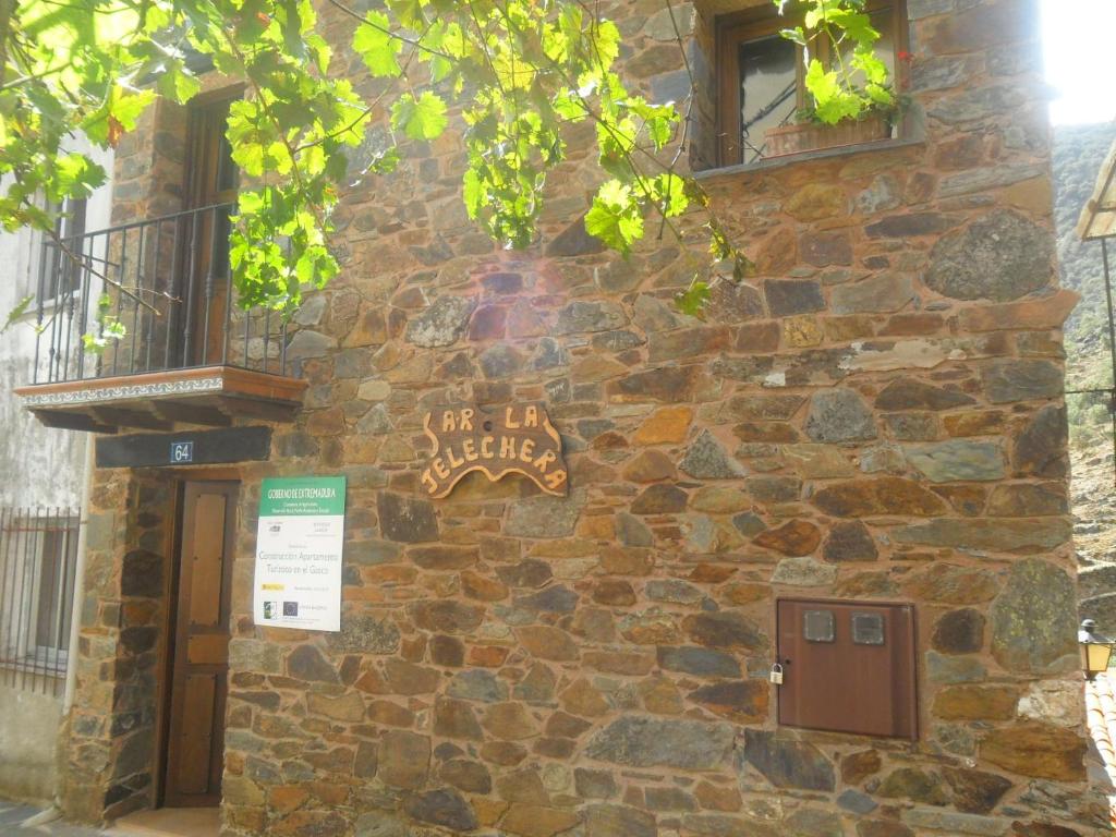 un edificio de piedra con un cartel en el costado en La Jelechera, en El Gasco