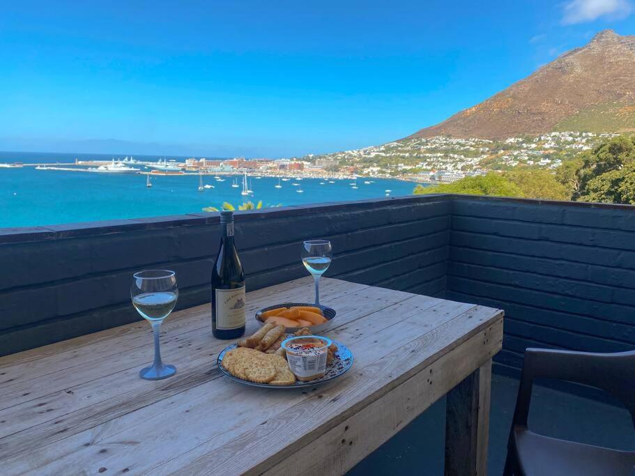 a table with a plate of food and a bottle of wine at Lock up & go apt w/ great views in Simons Town in Cape Town