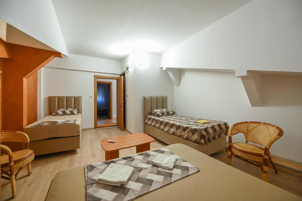 a room with two beds and a table and chairs at Hostel Izvor in Podgorica