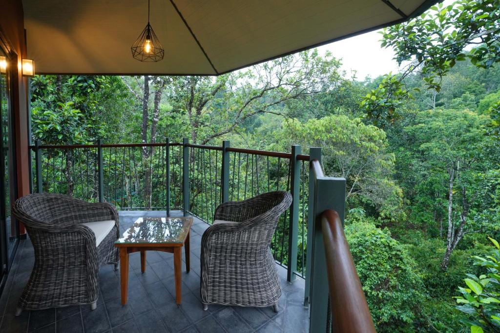 un porche con 2 sillas y una mesa en el balcón en Vyna Hillock Resort and Spa, en Vythiri