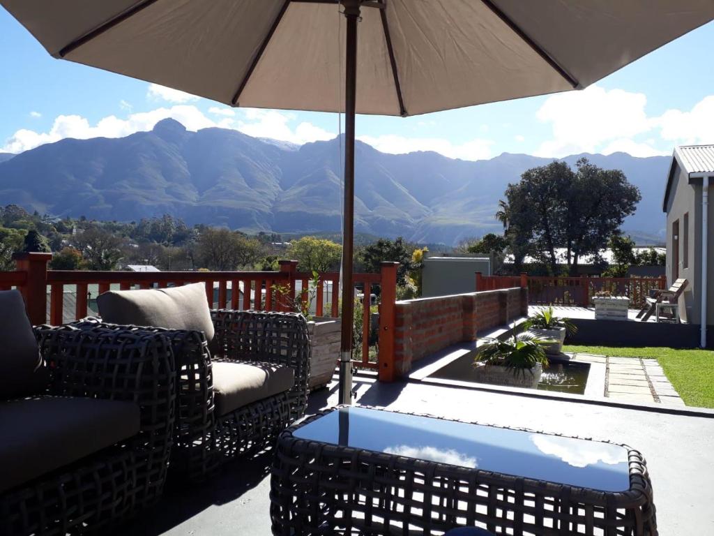 patio con sedie, ombrellone e montagne di 20 On Somerset a Swellendam