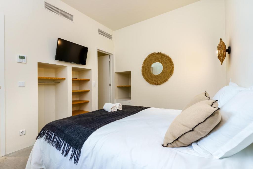 a white bedroom with a bed and a tv at La Réserve Comporta in Carvalhal