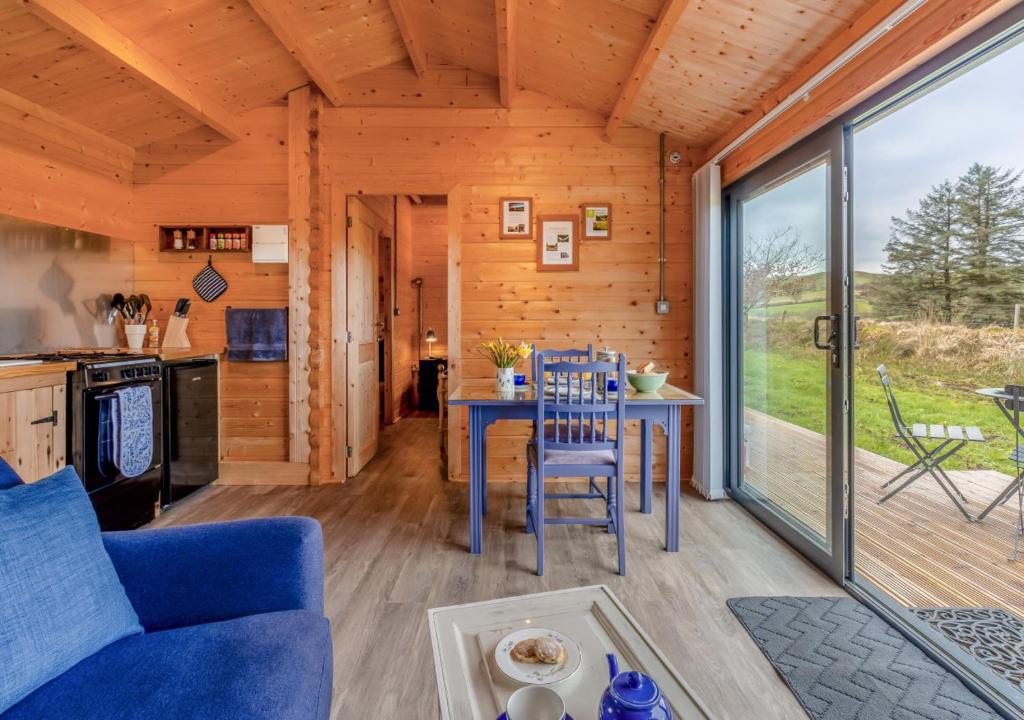 a living room with a blue couch and a table at Bluebell Cabin in Devils Bridge