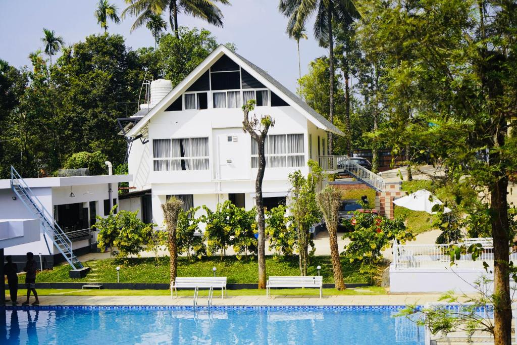 a white house with a pool in front of it at Brooke Forest Heaven Resort in Vythiri