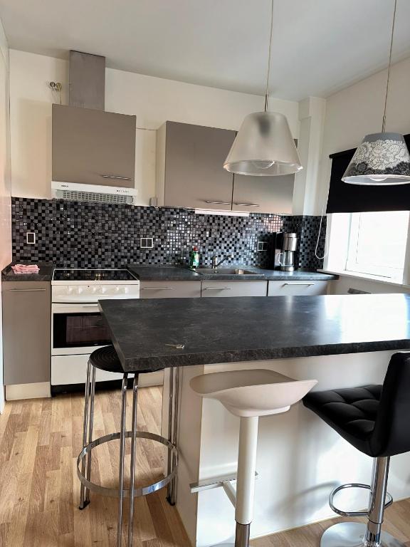 a kitchen with a black counter and stools at Grønne Esbjerg C in Esbjerg