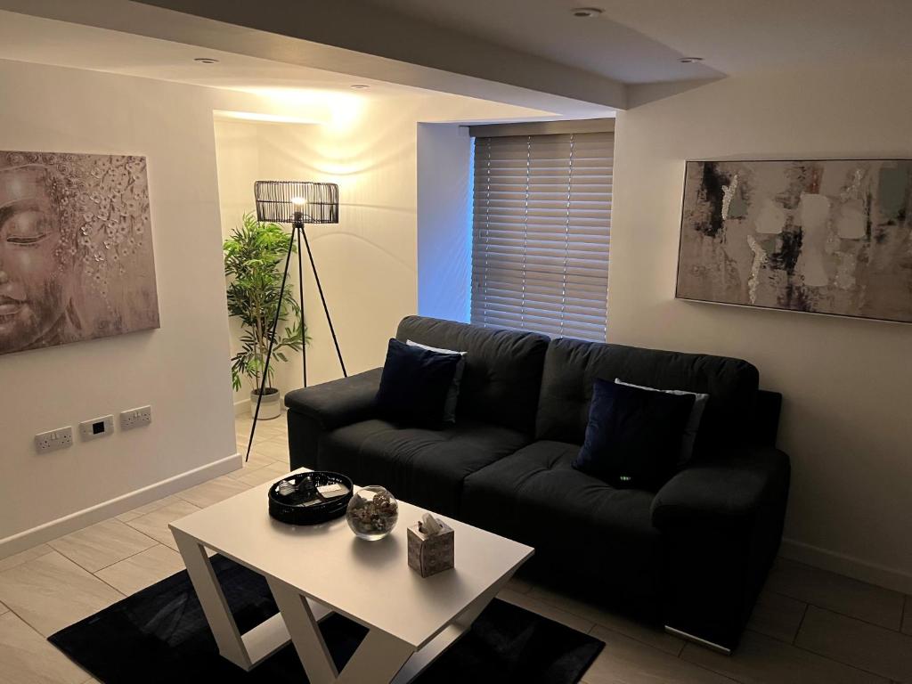 - un salon avec un canapé noir et une table dans l'établissement Stunning 1 Bedroom Apartment in Bicester Town, à Bicester