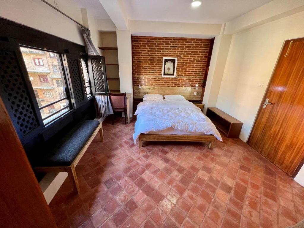 ein Schlafzimmer mit einem Bett und einer Ziegelwand in der Unterkunft Shahi Studio Apartment in Pātan