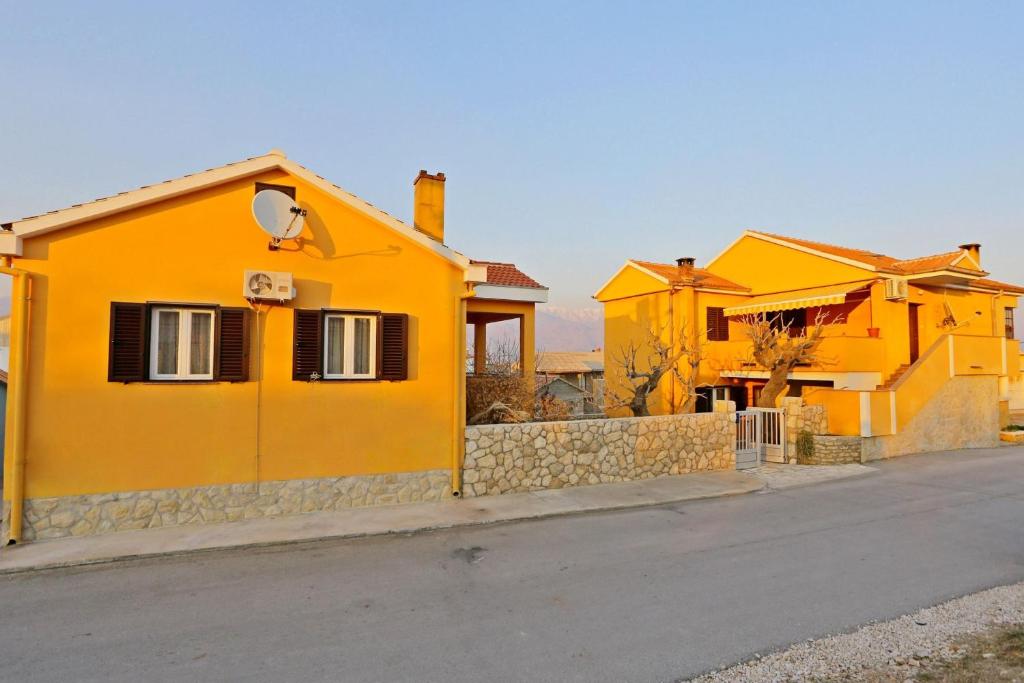 une maison jaune sur le côté d'une rue dans l'établissement Apartments Max, à Ražanac