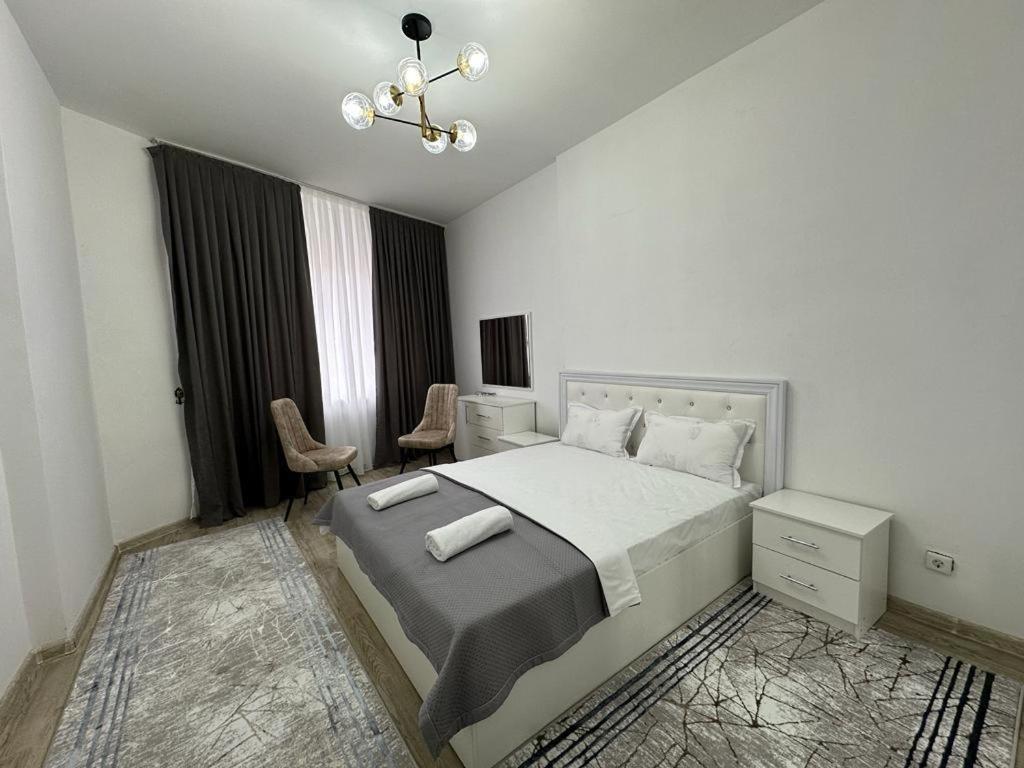 una camera da letto bianca con un letto e una sedia di Квартира a Türkistan
