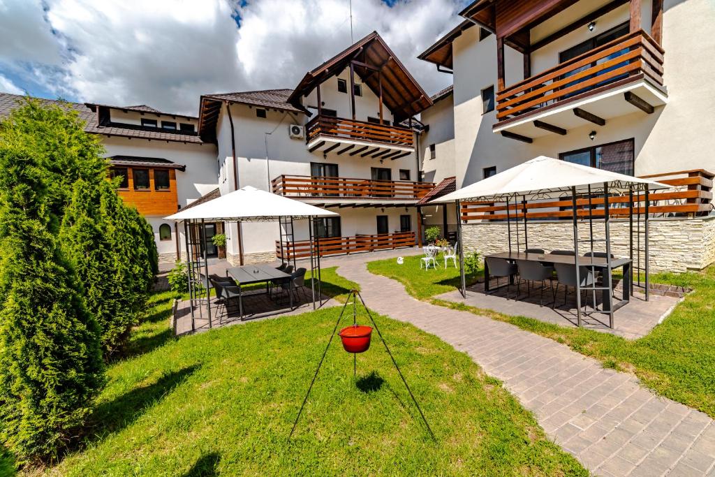 a house with a yard with tables and umbrellas at Yael Luxury Apartments 2 in Buşteni