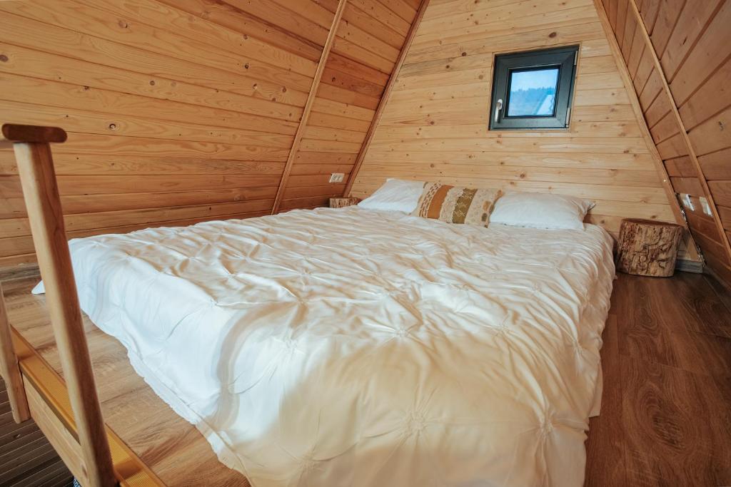ein Schlafzimmer mit einem Bett in einer Holzhütte in der Unterkunft Casuta Mea in Piatra Neamţ