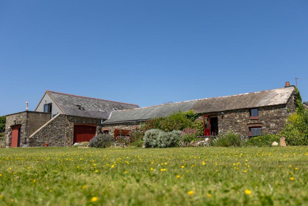 uma antiga casa de pedra com um campo verde em frente em Delfryn Holiday Cottages em Solva