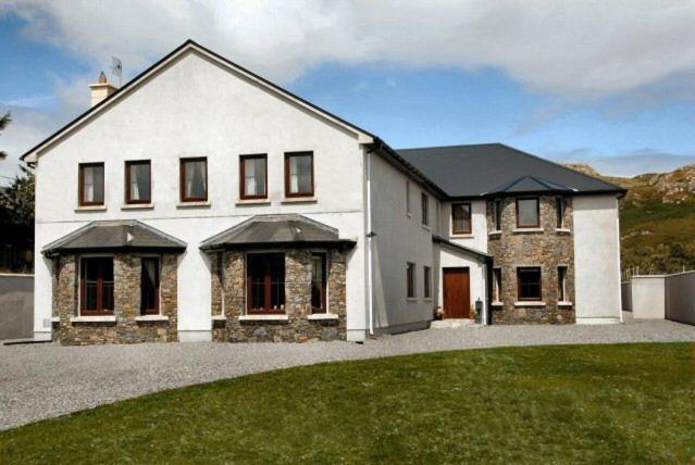 una gran casa blanca con un patio de césped en All the Twos Lodge en Clifden
