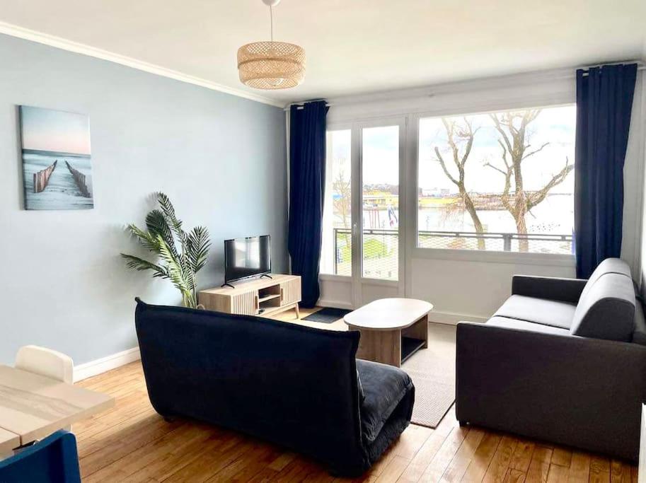 un salon avec deux canapés et une télévision dans l'établissement Côté Sable, un balcon sur la mer - parking inclus, à Boulogne-sur-Mer