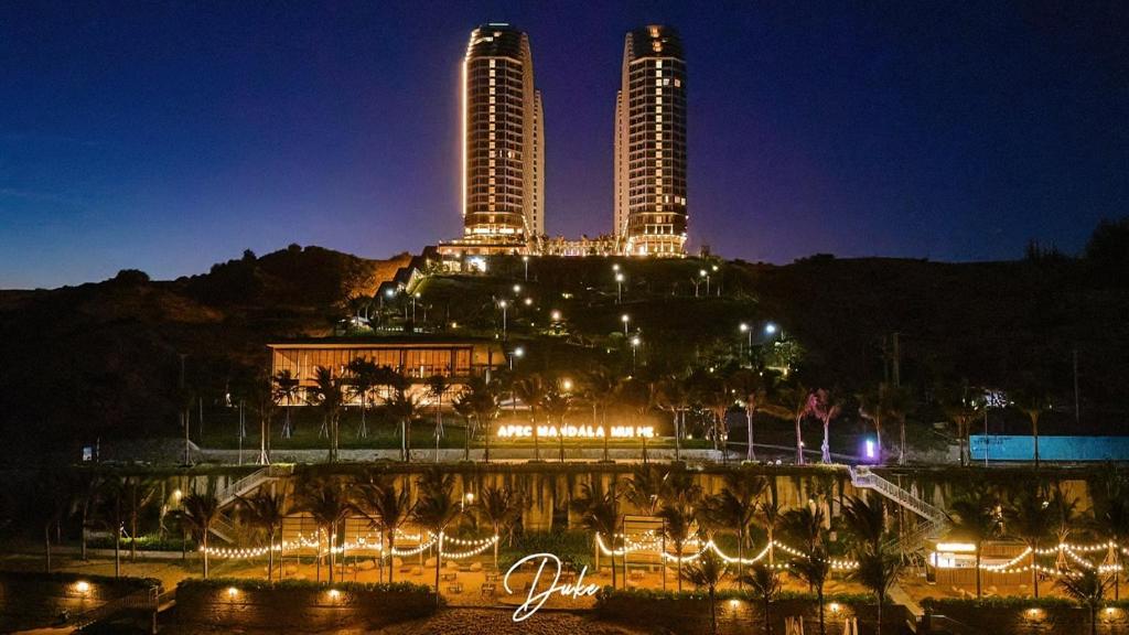 una vista de dos edificios altos por la noche en APEC MANDALA CDT - Resort en Phan Thiet