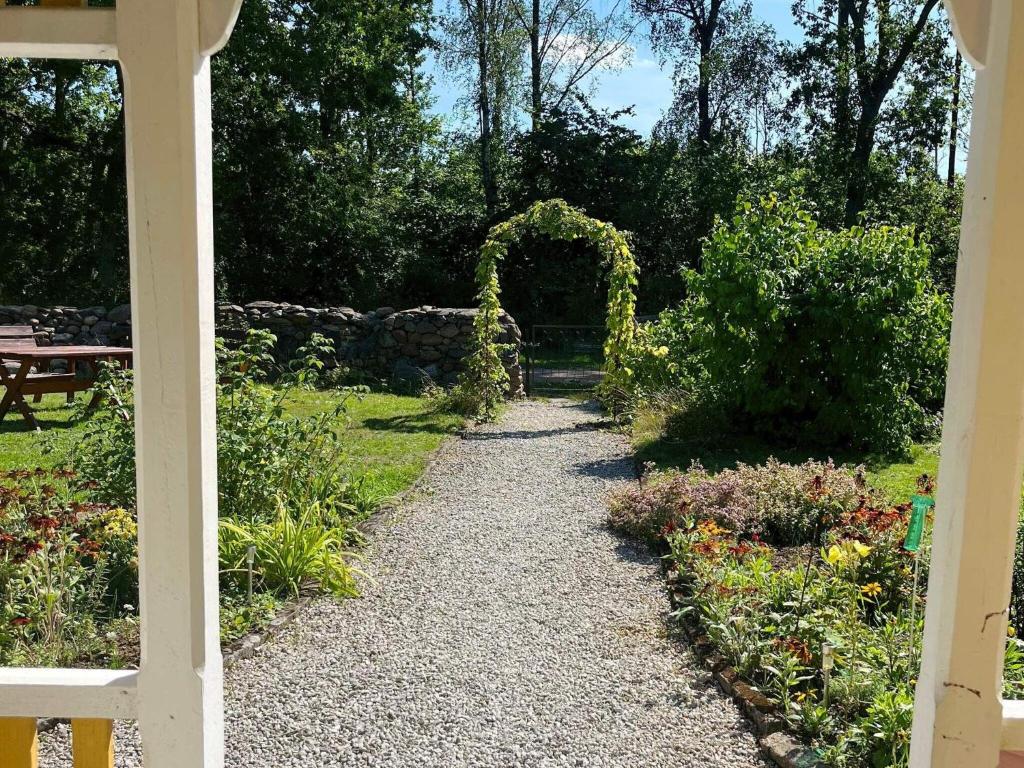 um jardim com um arco e um caminho de cascalho em Holiday home KLINTEHAMN IV em Klintehamn