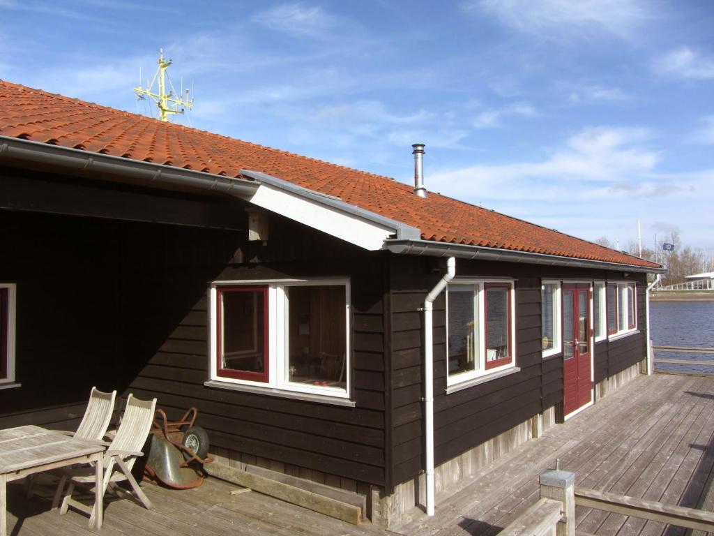 a black house with a deck next to the water at Boothuis Lauwersoog in Lauwersoog
