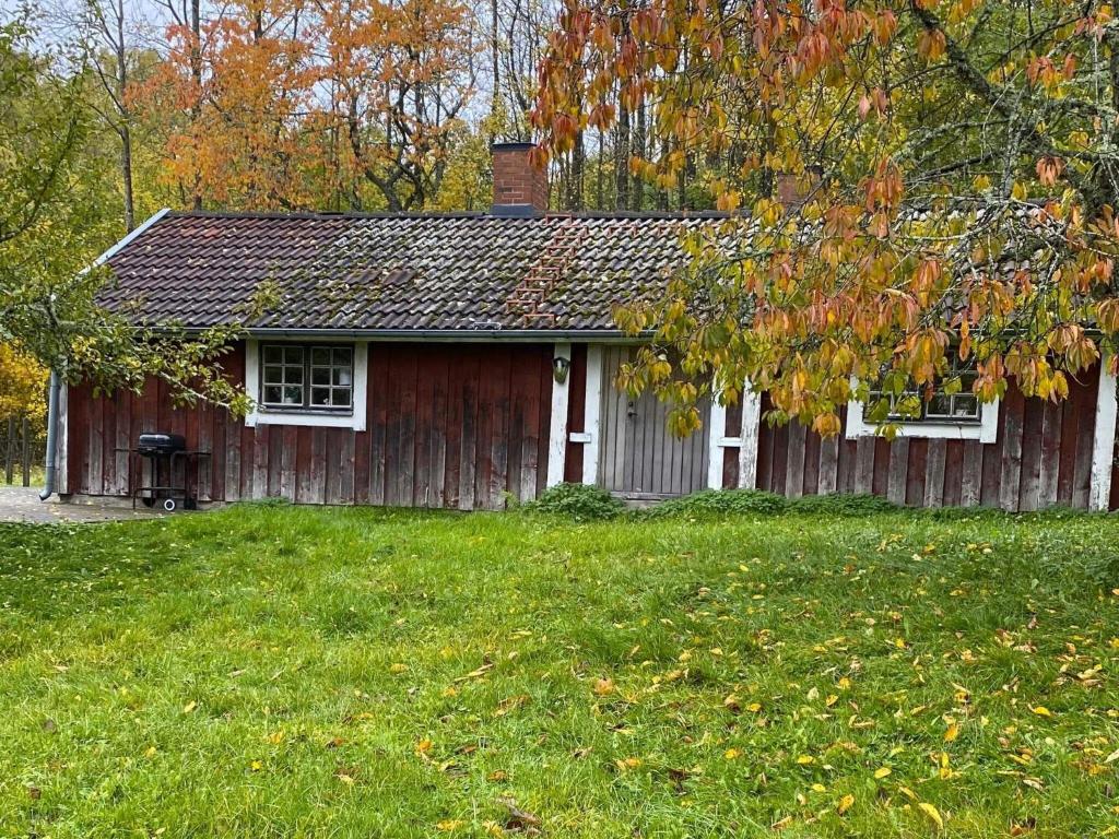 a small red house with a yard in front of it at Holiday home ANNEBY in Aneby