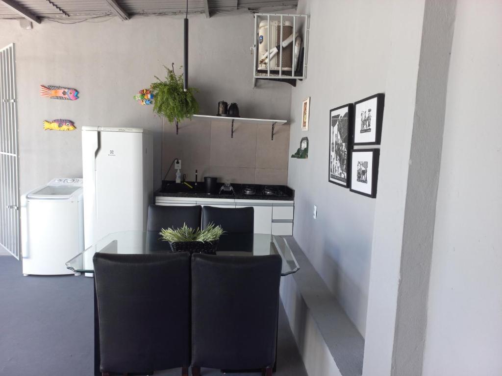 eine Küche mit einem Glastisch und schwarzen Stühlen in der Unterkunft Linda edícula a 80 m da Praia de Itapuã in Salvador