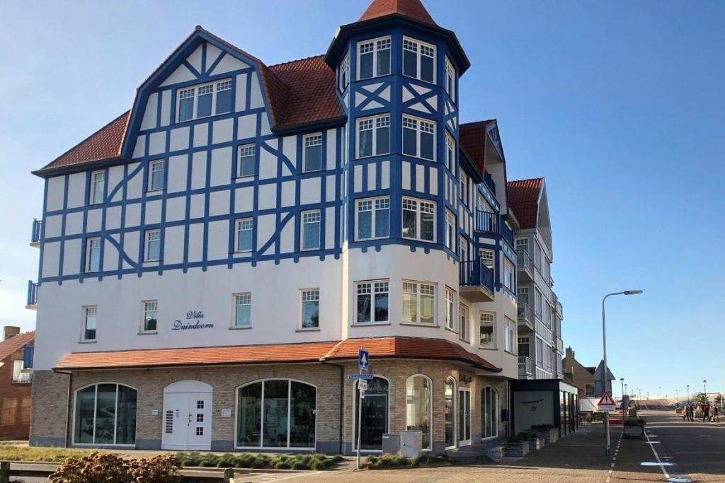 un gran edificio con una torreta en una calle en Villa Duindoorn 2.302, en Cadzand