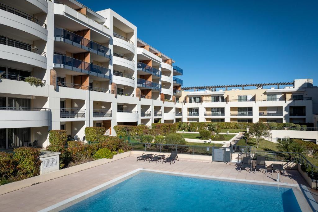 un immeuble d'appartements avec une piscine en face dans l'établissement Nemea Appart Hotel Le Lido Cagnes sur Mer, à Cagnes-sur-Mer