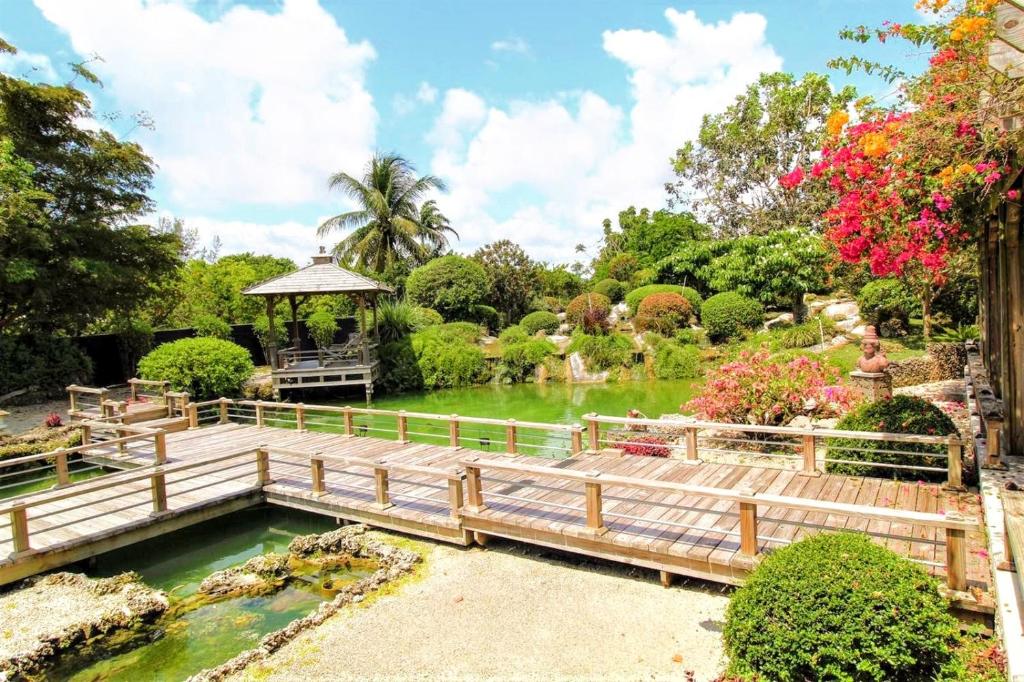 un pont sur un étang et un kiosque dans un jardin dans l'établissement Exclusive Lake Tiny House in Beautiful Japanese Garden, à Homestead