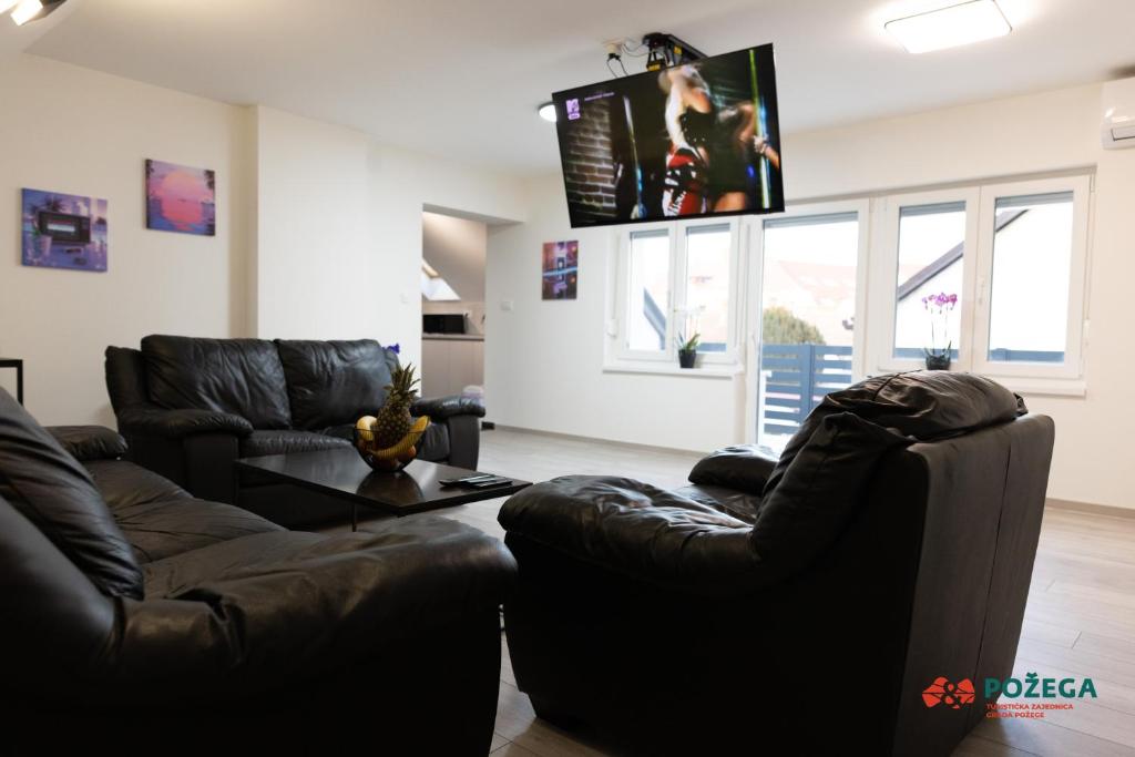 a living room with two leather chairs and a table at Apartment Eden in Požega