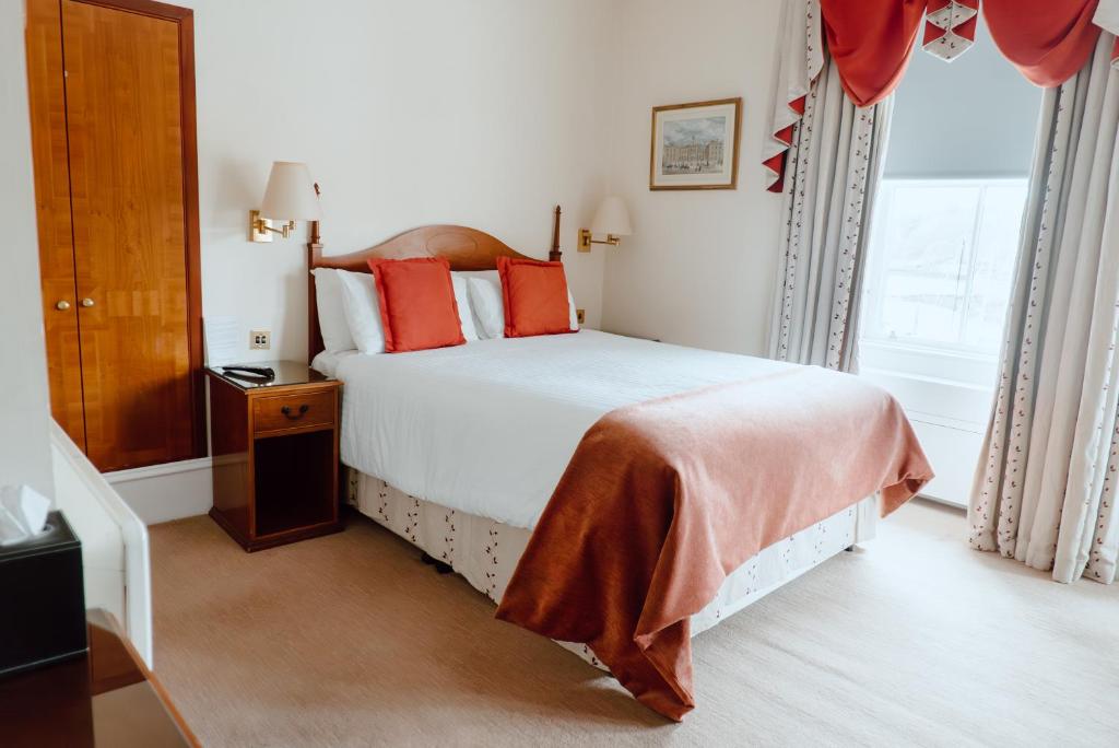 een slaapkamer met een groot wit bed met rode kussens bij Royal Hotel in Stornoway