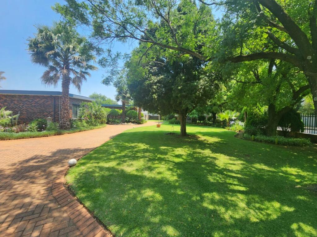 a lawn with trees and a brick road at OR Tambo Rudman B self-Catering Home L2 in Boksburg