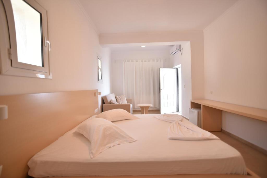 a white bedroom with a bed and a chair at Dima Vista in Dhërmi