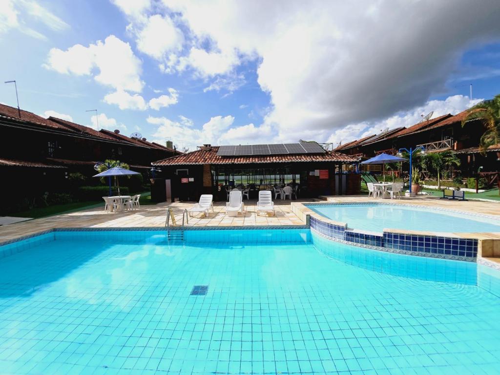 uma grande piscina com cadeiras e um edifício em Chalé do Paraiso - Casa bem Equipada e Confortável para seu Lazer em Gravatá! em Gravatá